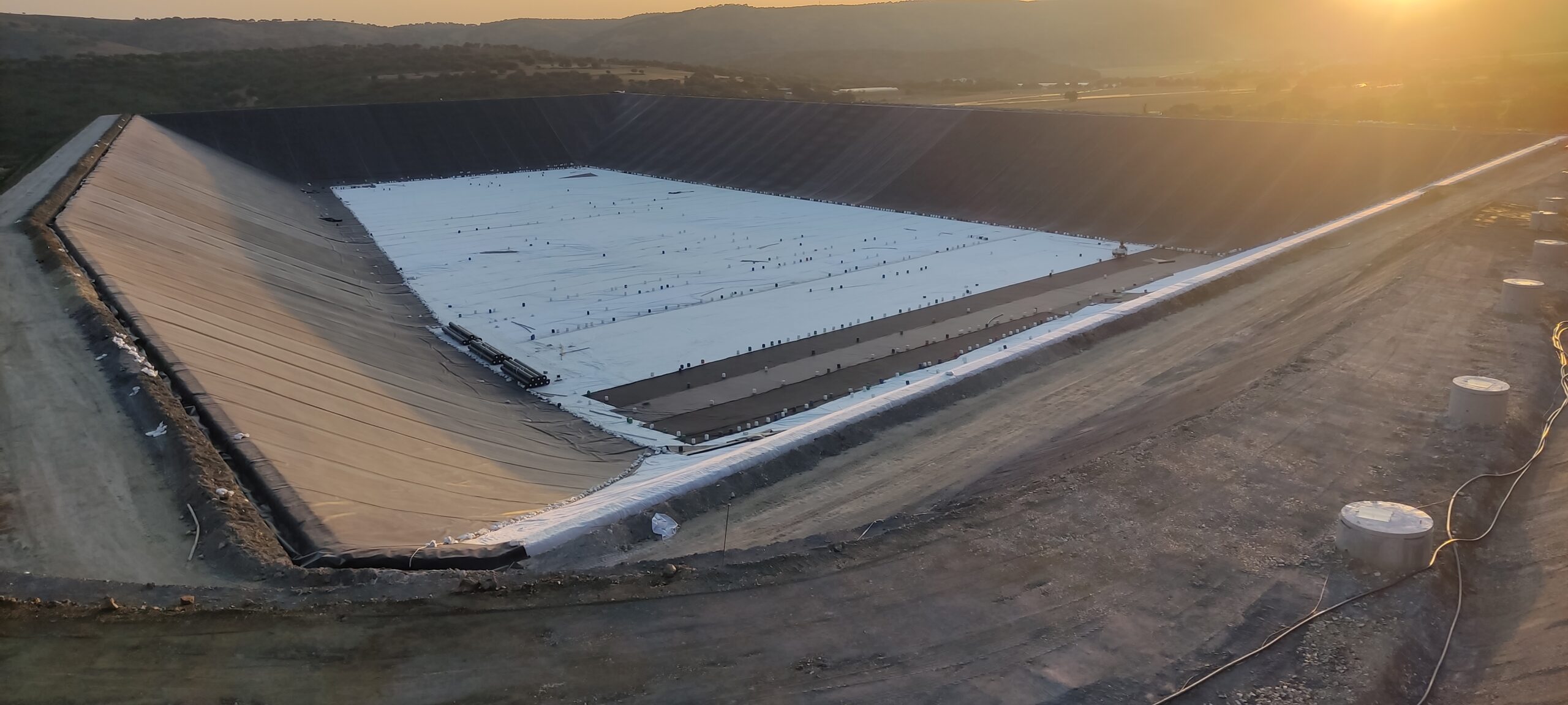 Balsa con geotextil y geomembrana al atardecer